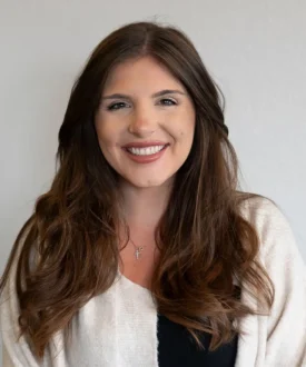 Smiling woman with long brown hair wearing a white sweater, representing Cool Roofs' friendly customer service for roofing inspections and hail damage repairs.