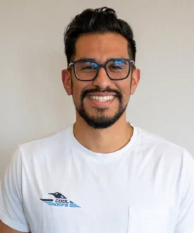 Man smiling in a white shirt with "Cool Roofs" logo, representing roofing services and expertise in hail damage inspections.