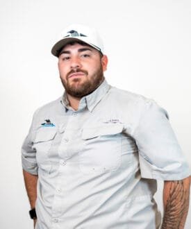 Man wearing a Cool Roofs branded shirt and cap, standing confidently, representing roofing services focused on hail damage inspections and repairs.
