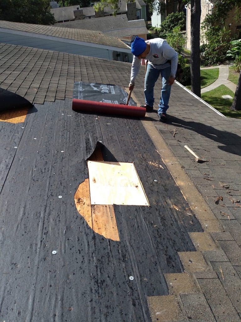 Roofing contractor applying repair materials on a residential roof in San Antonio, demonstrating expertise in roof maintenance and repair services.