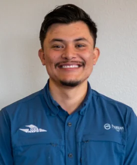 Smiling man in blue work shirt representing Cool Roofs, emphasizing roofing service expertise and customer engagement.