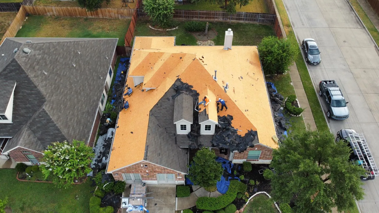 Roof repair in progress on a Texas home, showing workers replacing shingles and inspecting for damage, with tools and materials visible on the roof and surrounding area.