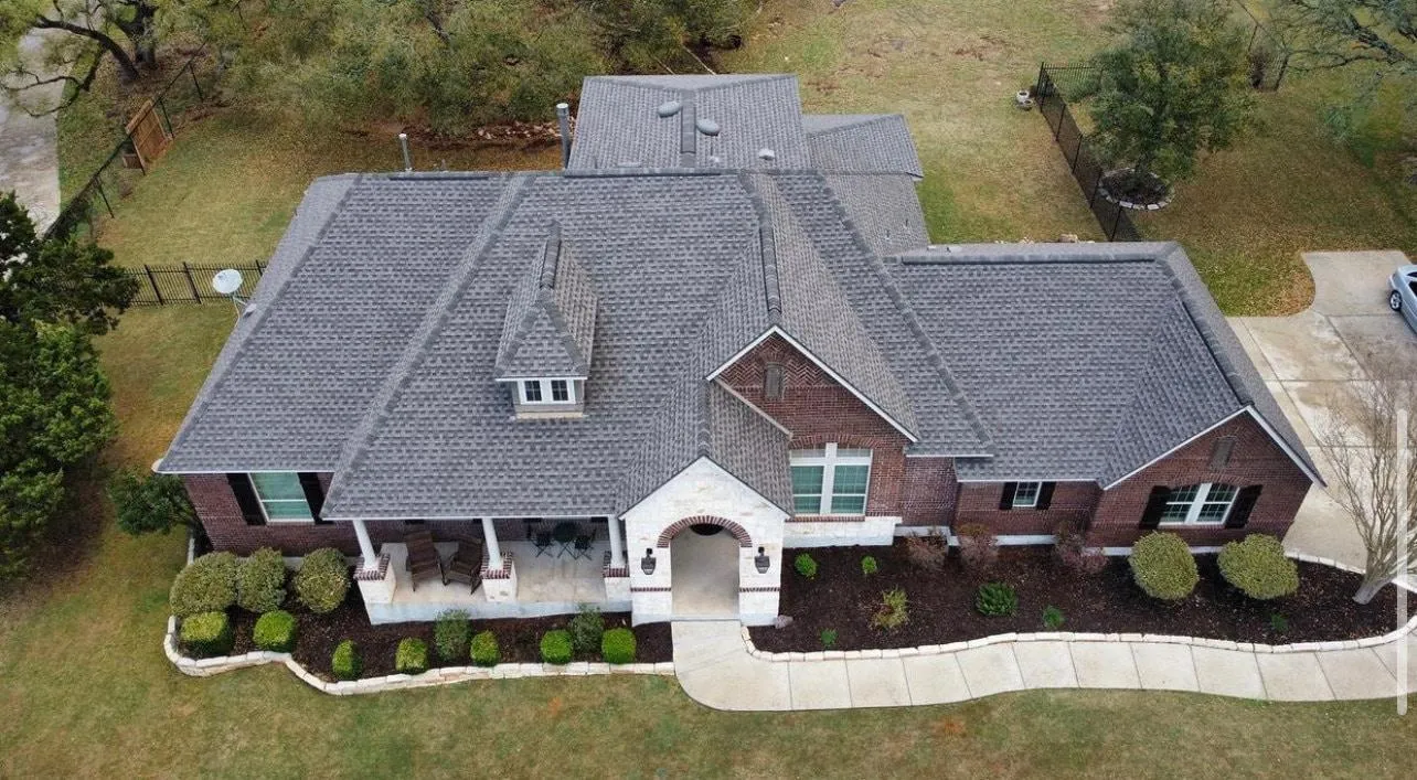 Aerial view of a large, modern brick house with a well-maintained yard